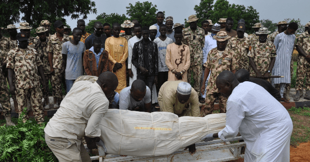 Nigerian soldiers and relatives look on as the body of a victim of the attack on vehicles carrying Borno governor Babagana Umara Zulum near the town of Baga on the shores of Lake Chad is buried during a the funeral in Maiduguri on September 26, 2020. - The insurgents opened fire with machine guns and rocket-propelled grenades as the convoy was passing through a village close to the headquarters of the Multinational Joint Task Force (MNJTF), a military coalition of troops from Nigeria, Niger, Chad and Cameroon.