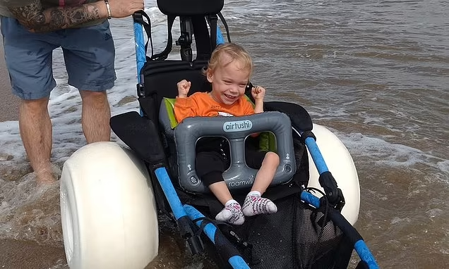 Heartwarming moment boy, two, with cerebral palsy plays in the sea for the first time thanks to high-tech waterproof wheelchair