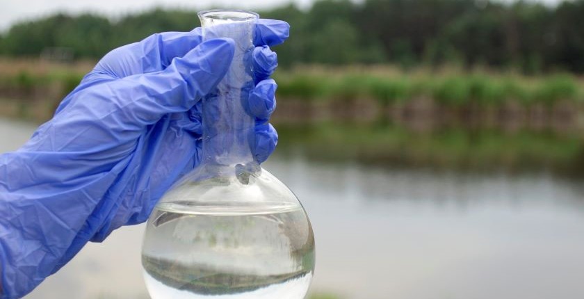 Contaminated tap water flowing from a household faucet in a Serbian village near Zrenjanin, with bottled water containers visible, illustrating long-term water pollution and lack of safe drinking water.