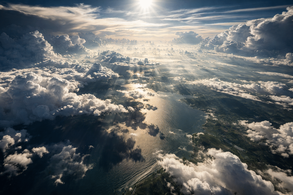 High-altitude aerial view of layered clouds casting shadows over Earth’s surface, illustrating global weather and climate-related themes.