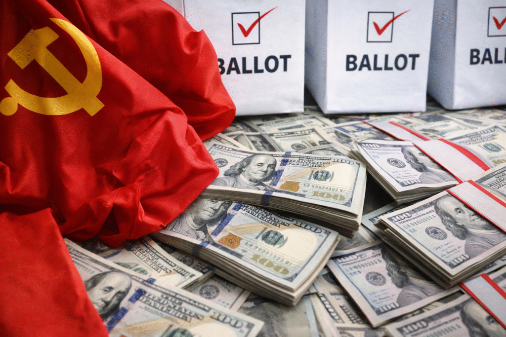 Stacks of U.S. hundred-dollar bills lie beneath ballot boxes while a Chinese Communist Party flag is draped across the scene, symbolizing foreign money and election influence.