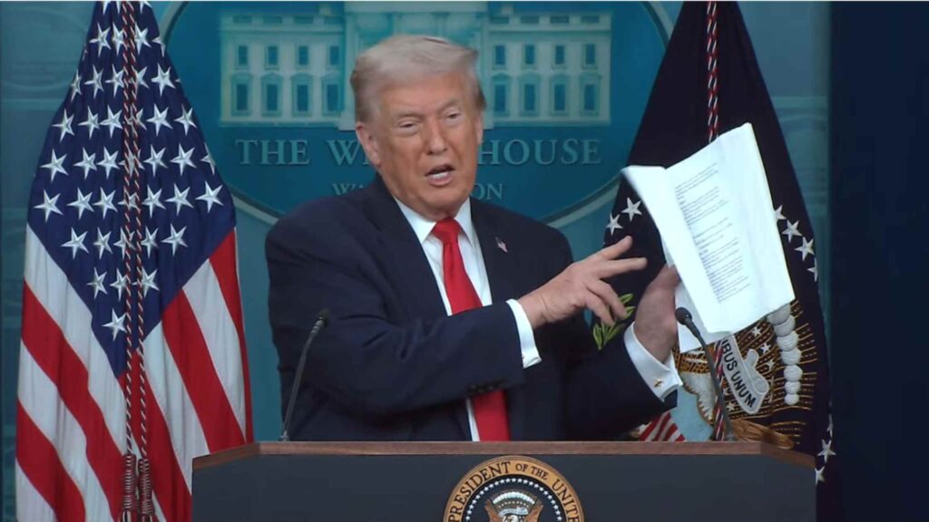 President Donald Trump speaking at a White House podium during a press briefing.