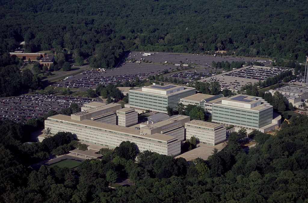 Exterior of the Central Intelligence Agency headquarters in Langley, Virginia, with the CIA seal visible on the building façade in daylight.