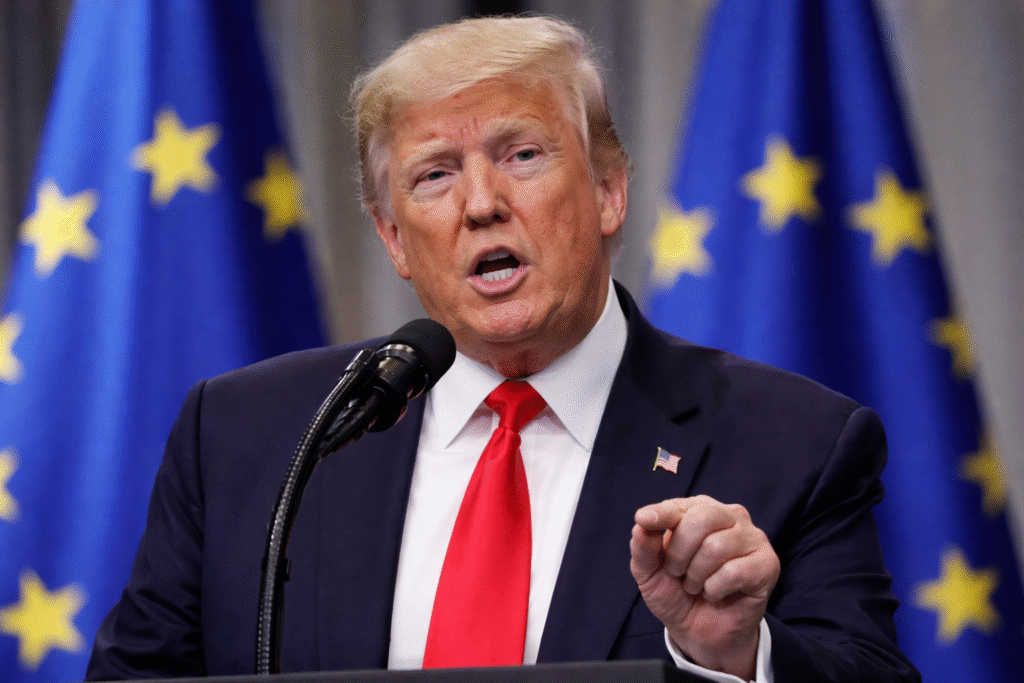 President Donald Trump speaking at a podium with European Union flags in the background, addressing trade and tariff policy.