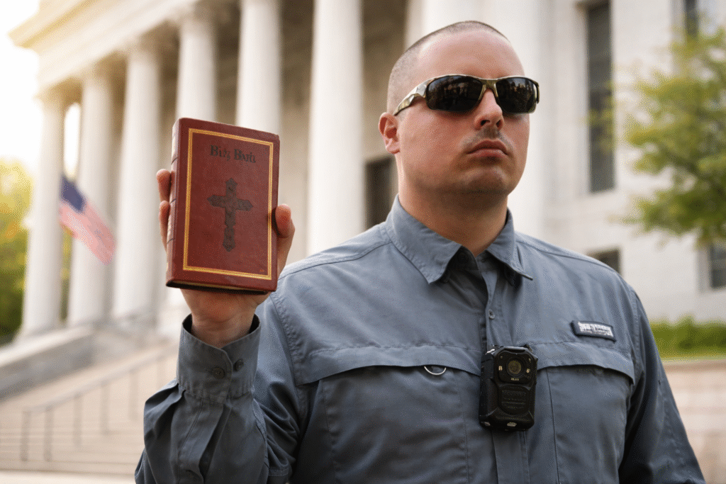 Man wearing sunglasses holding a Bible outside a courthouse, representing a religious liberty legal case.