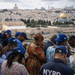 Christian pilgrims visiting and praying near historic holy sites in Jerusalem overlooking the Old City.