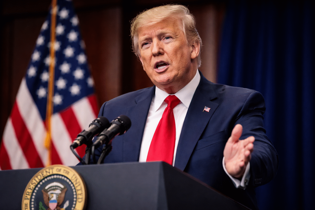 Photograph of President Donald Trump speaking at a podium with a U.S. flag behind him, symbolizing his announcement about the projected four-week duration of the military campaign involving Iran.