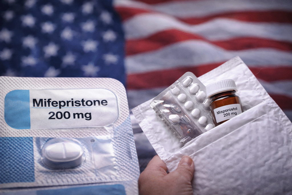 Blister pack labeled mifepristone beside abortion pills and a prescription bottle in a mail envelope, with an American flag in the background.