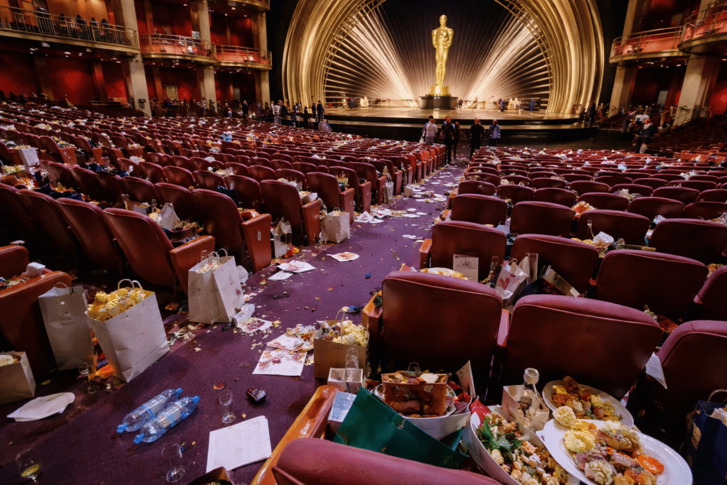 Auditorium at the Dolby Theatre after an awards ceremony with rows of seats and aisles covered in discarded food containers, bags, and trash.