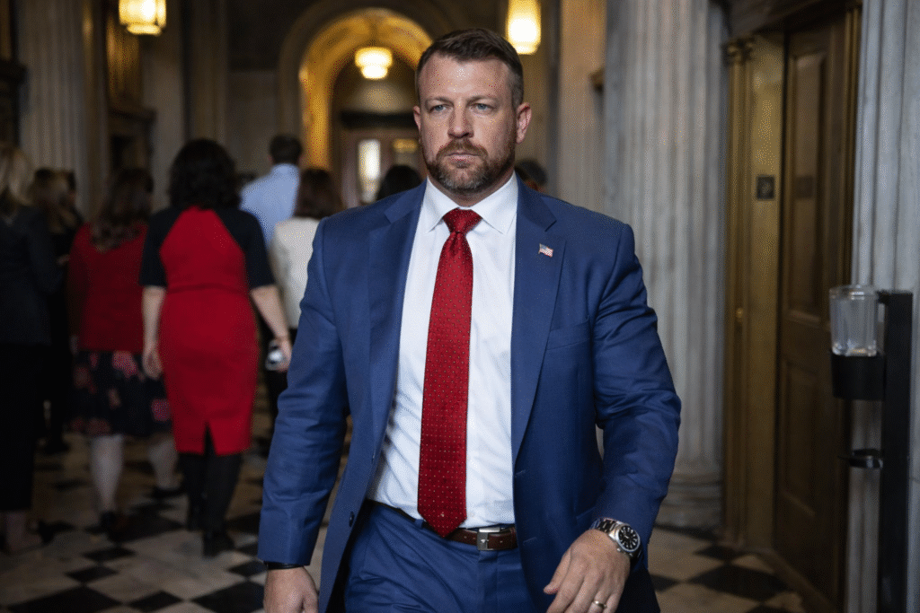 Man in blue suit and red tie walking through a government building hallway with people in the background
