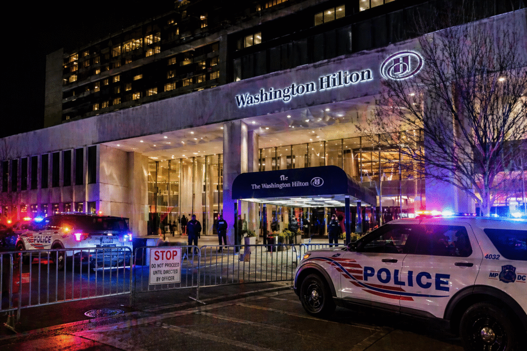 Security presence outside a large hotel venue at night with police lights and guarded entrances following a reported incident.