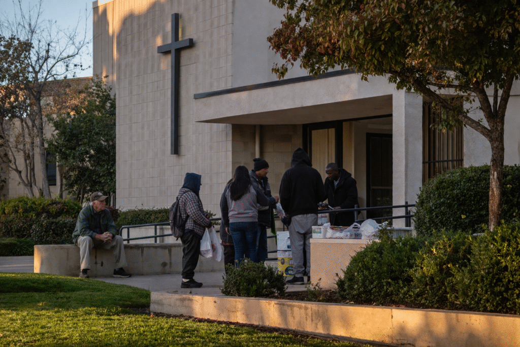 Exterior of a Catholic charity office with a small group of people gathered outside, representing faith-based social services and community assistance.