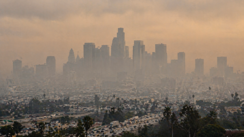 City skyline obscured by thick smog with heavy haze over buildings and traffic on a busy freeway below