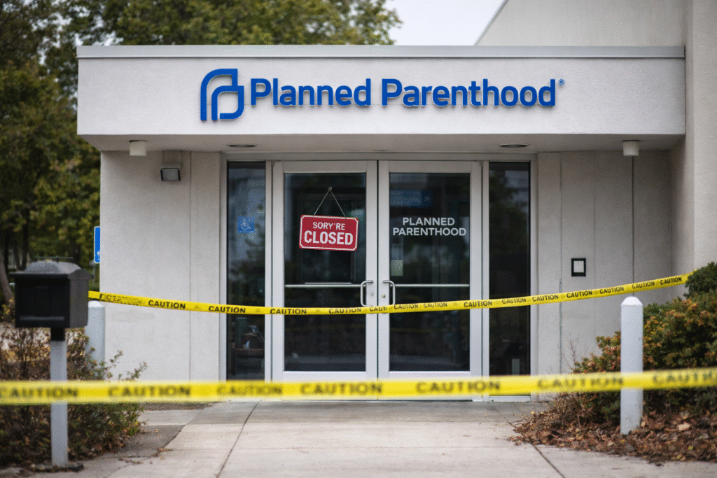 Exterior of a Planned Parenthood clinic with a closed sign on the door and caution tape blocking the entrance, indicating the facility has shut down