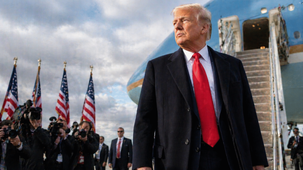 President Donald Trump standing on an airport tarmac near a presidential aircraft with American flags and photographers in the background