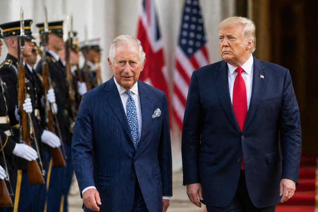 King Charles III and President Donald Trump walking side by side during a formal ceremony, with uniformed guards and U.S. and UK flags in the background.