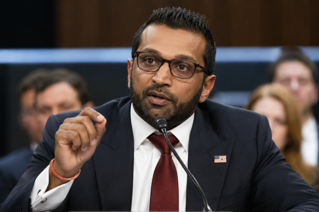 Kash Patel speaking during a formal government hearing while seated at a microphone in a wood-paneled chamber.