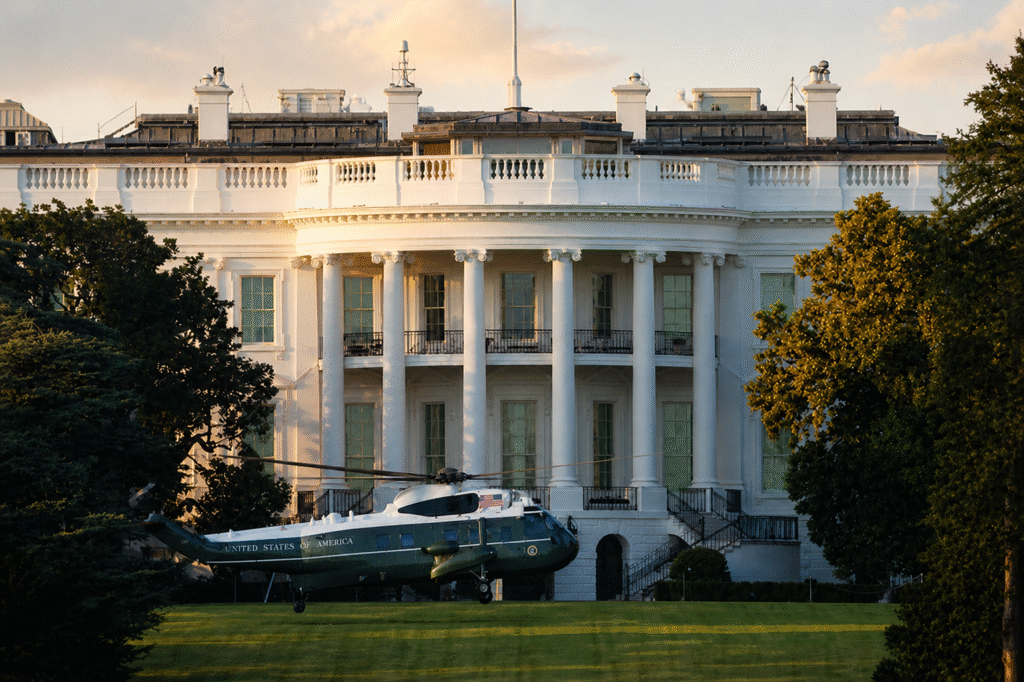 White House exterior at sunset with Marine One helicopter parked on the lawn, no people visible and no active fountain or water spray.